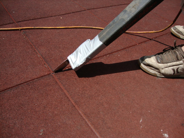 Close up image of cleaning the seams with a putty-knife taped to the end of a blower